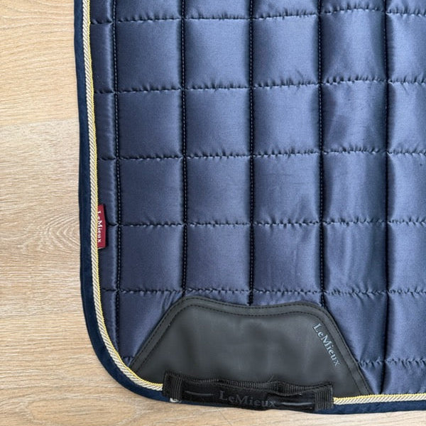 A close-up of a quilted navy blue horse saddle pad