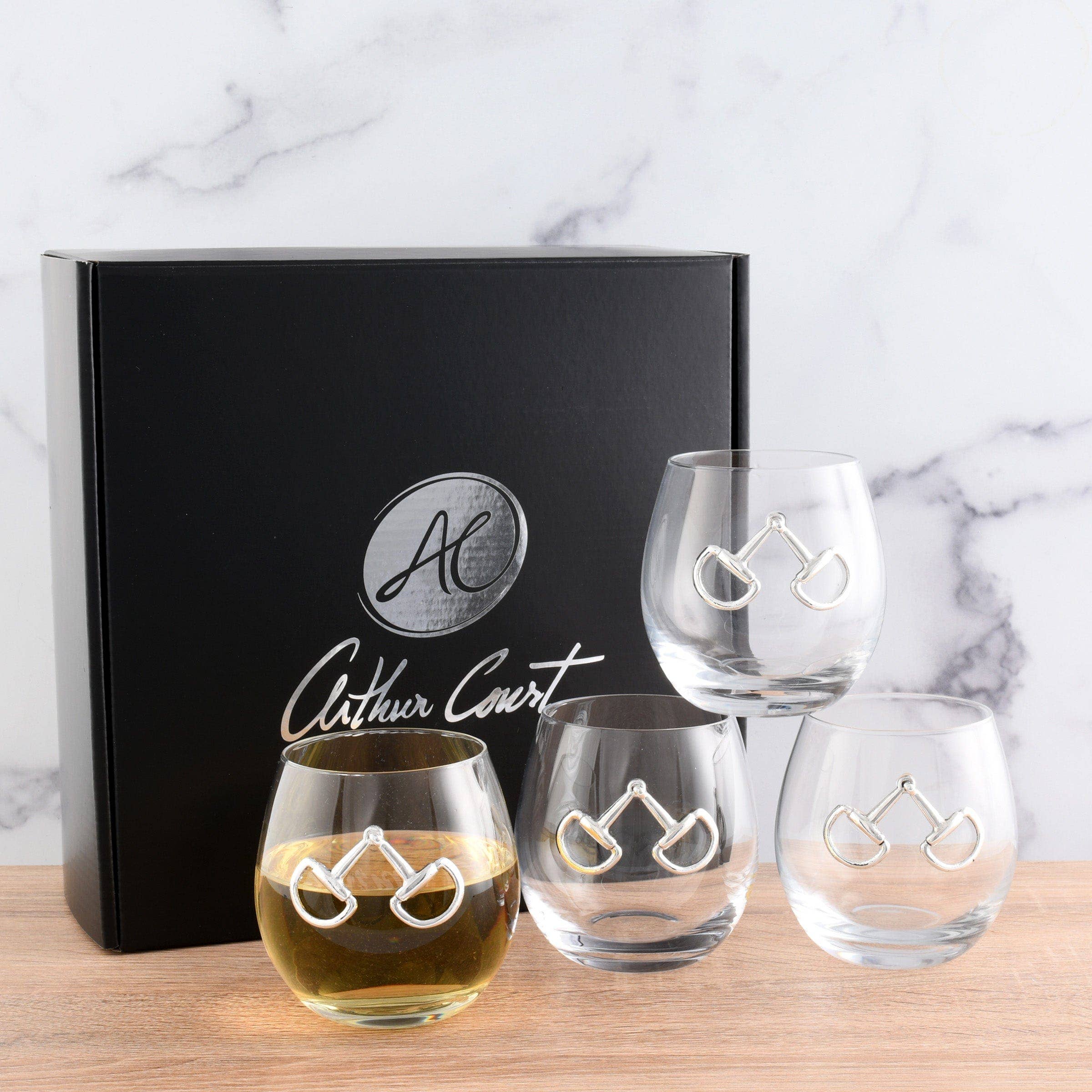 Set of stemless wine glasses with bicycle design on a marble surface, featuring the Arthur Court logo.