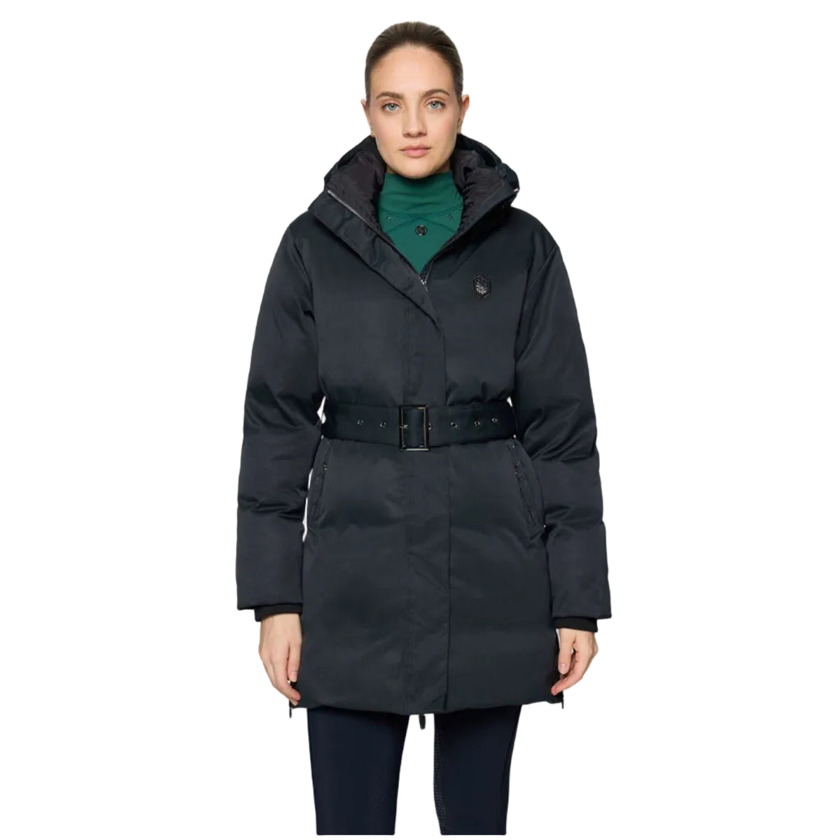 A woman modeling a black hooded puffer coat with a matching belt, worn over a green turtleneck sweater, against a light gray studio background.