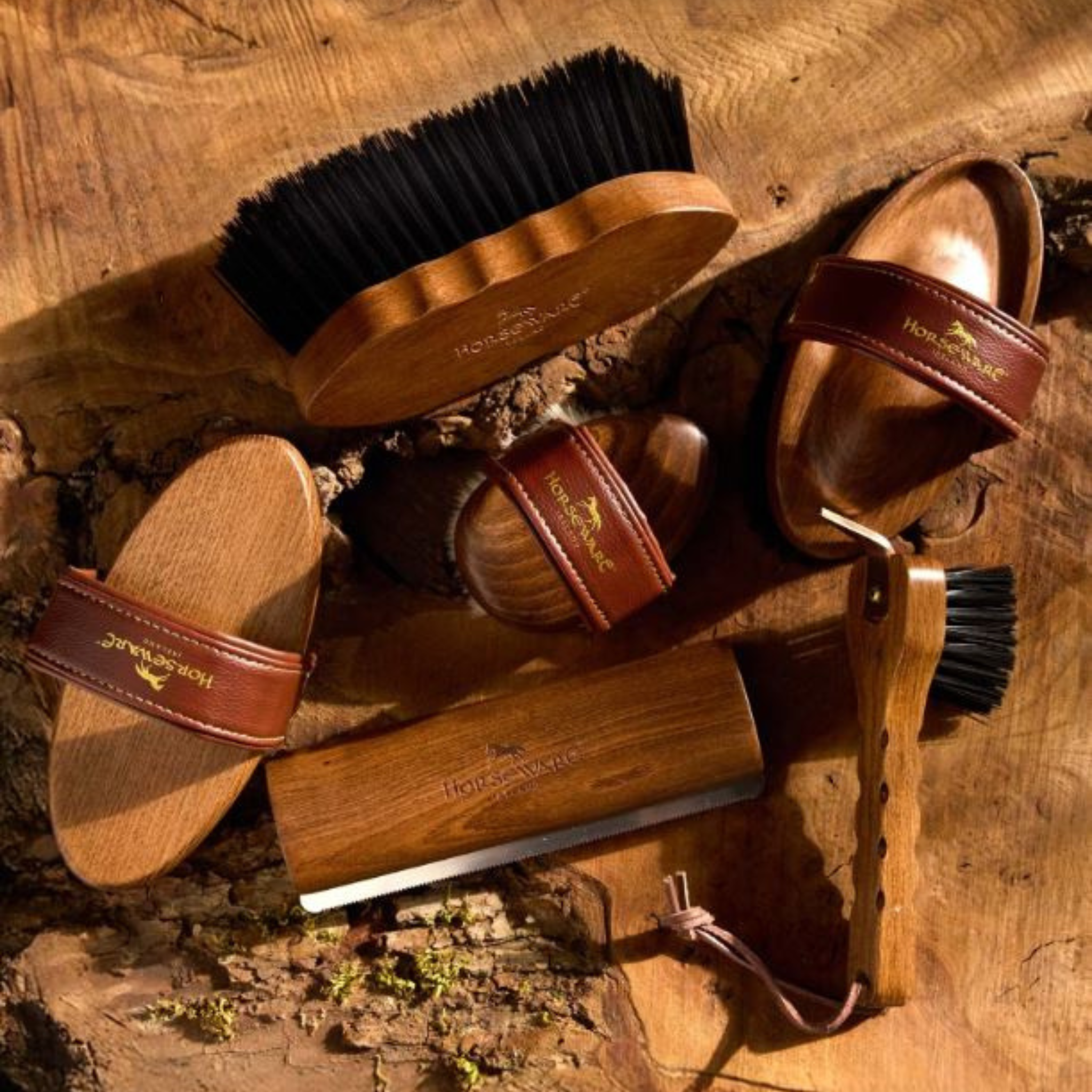 Set of horse grooming tools including brushes and a scrubber on a wooden surface.