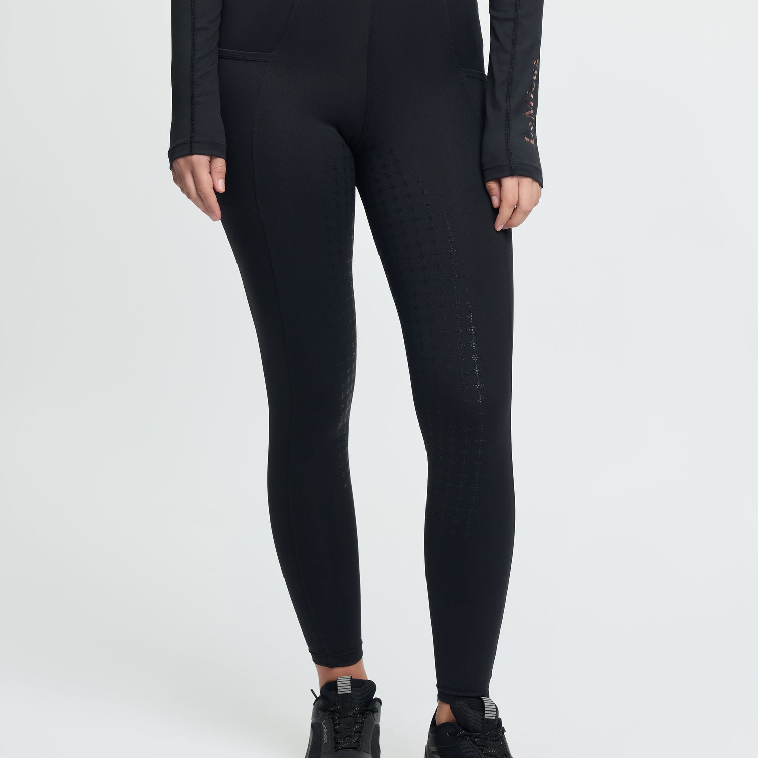 Person wearing black leggings and black shoes on a white background