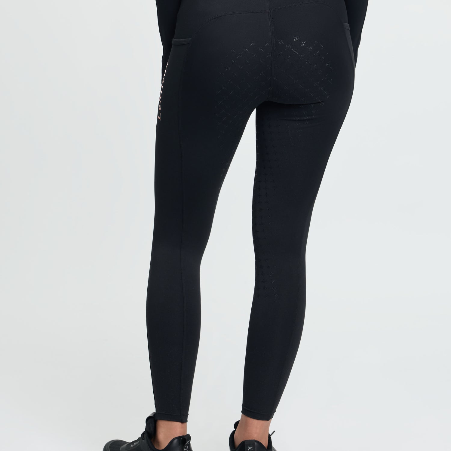 Person wearing black leggings with a visible brand logo on a white background
