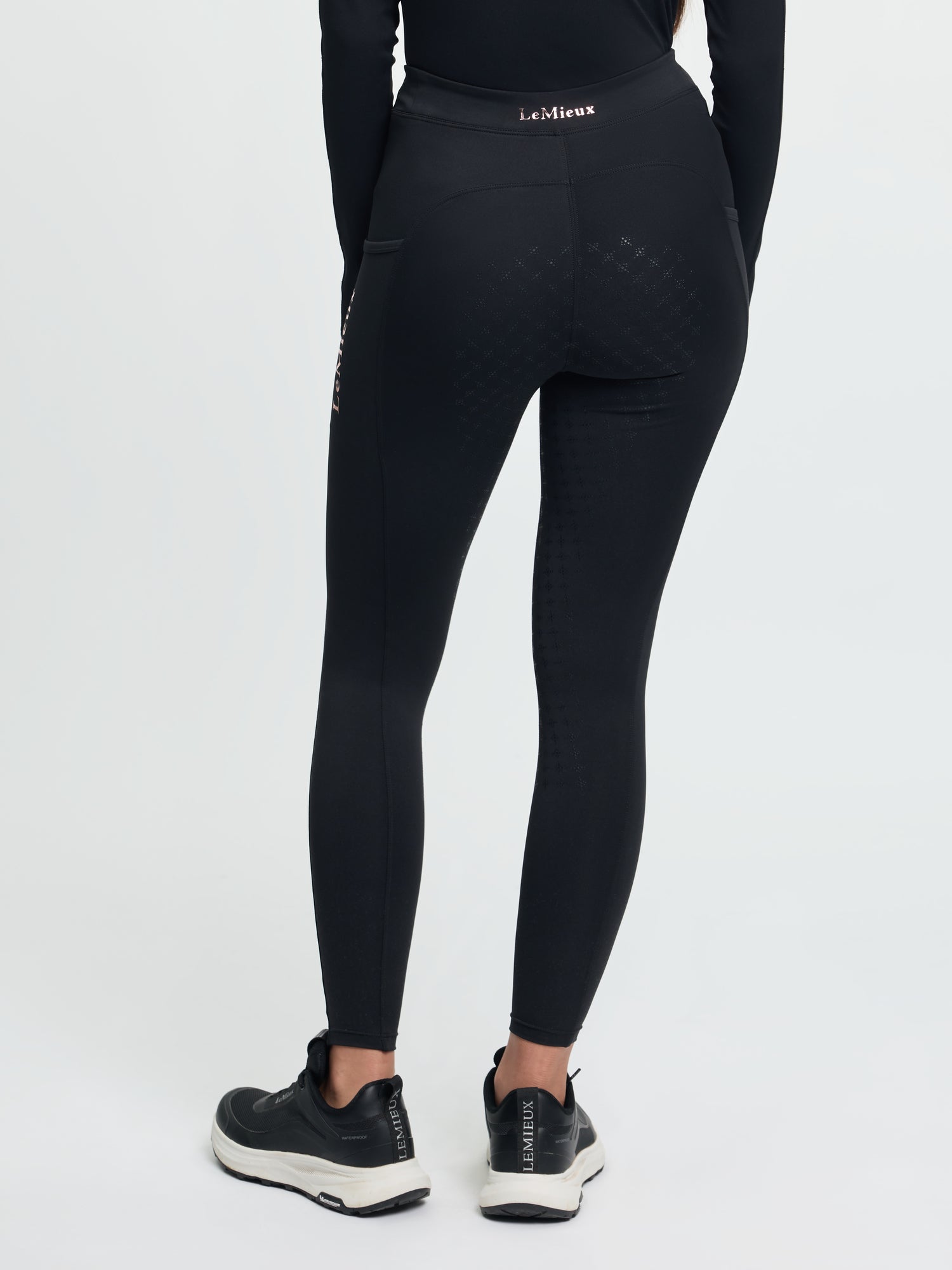 Person wearing black leggings with a visible brand logo on a white background