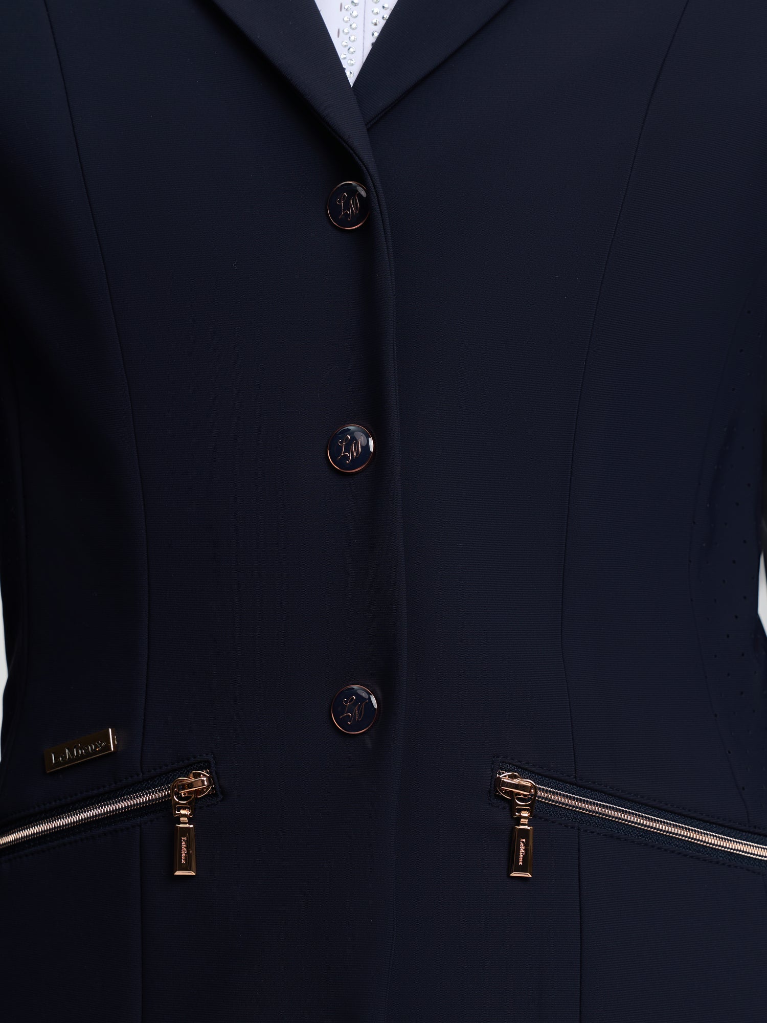 Navy blue blazer with gold zippers and buttons on a white background
