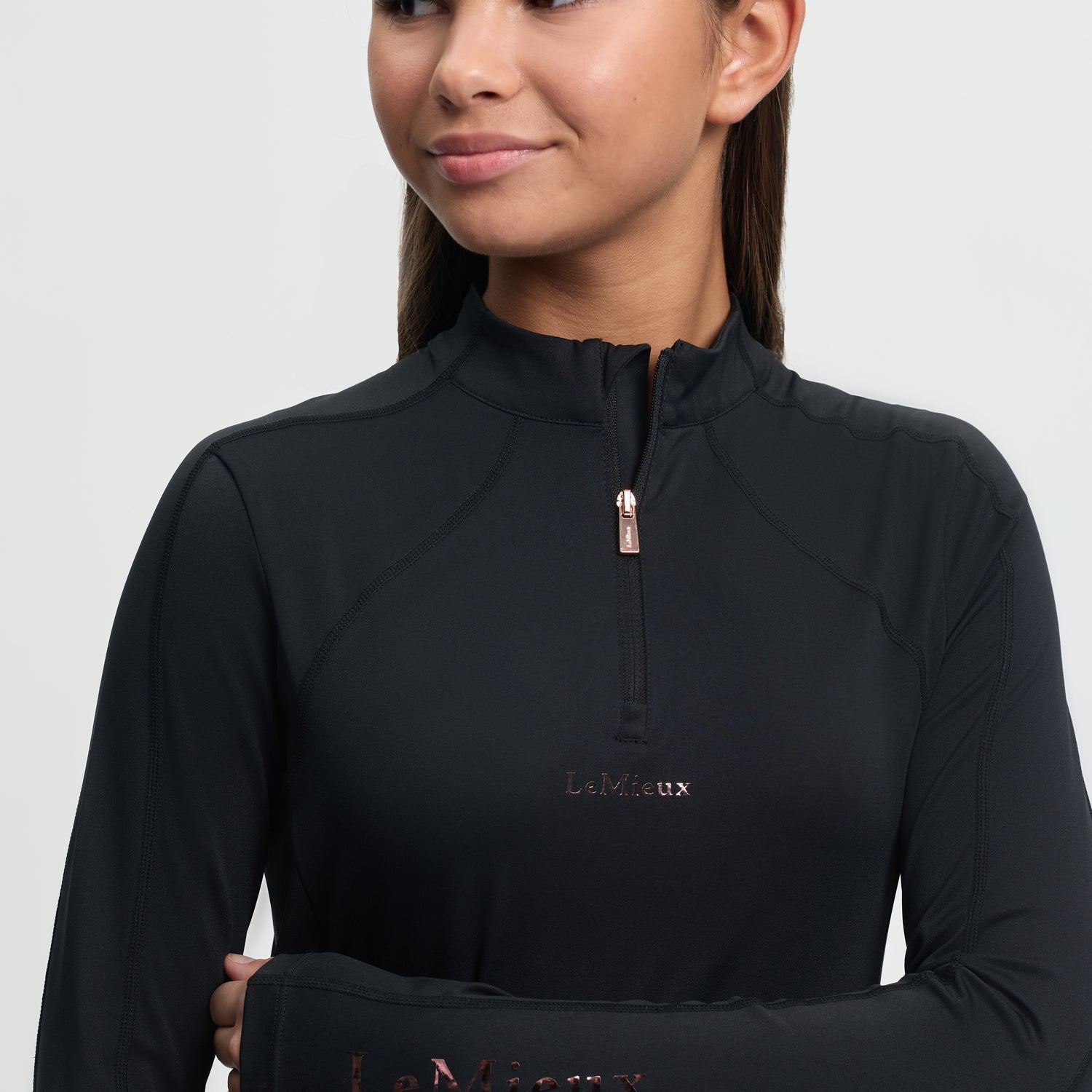 Woman wearing a black long-sleeve top with 'LeMieux' branding on a light gray background
