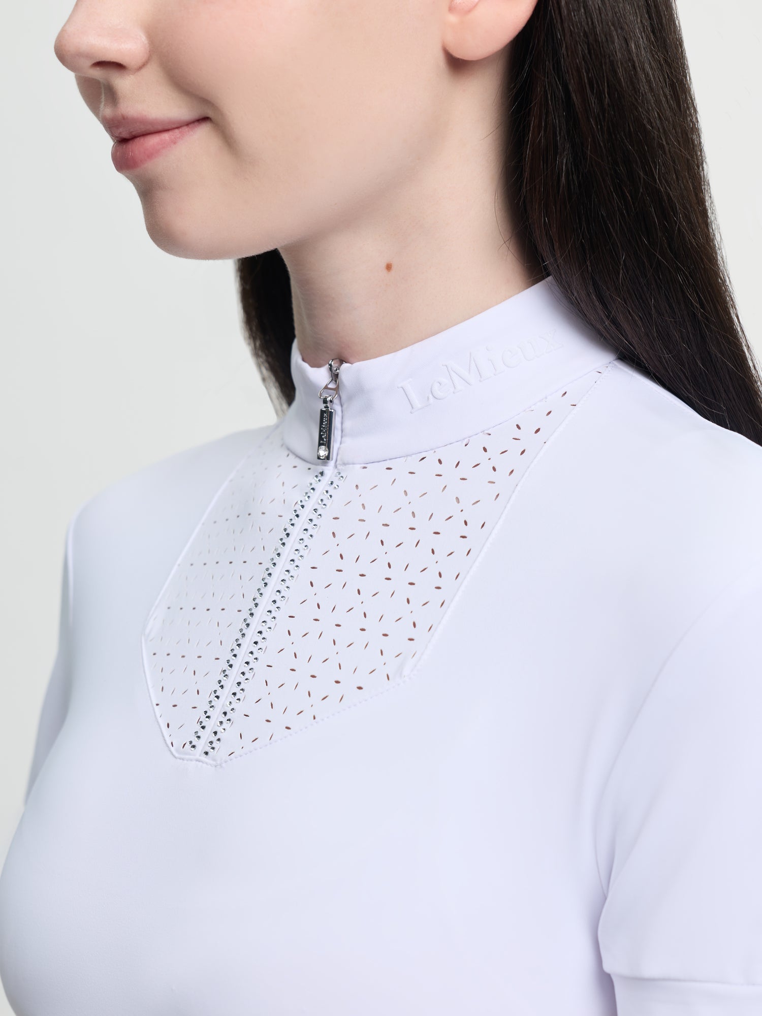 Close-up of a person wearing a light blue blouse with intricate detailing on a plain background