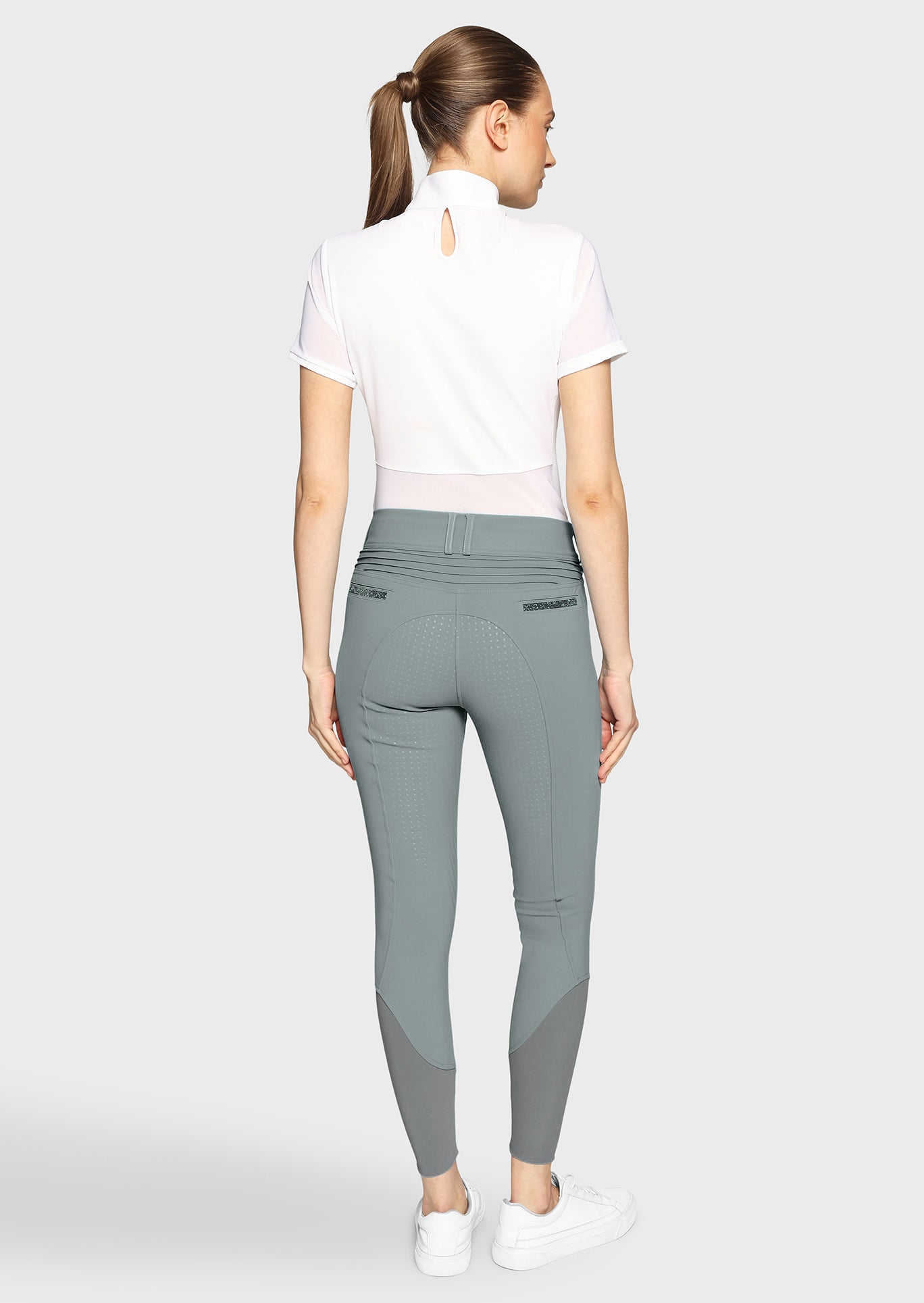 Woman wearing gray riding pants on a white background