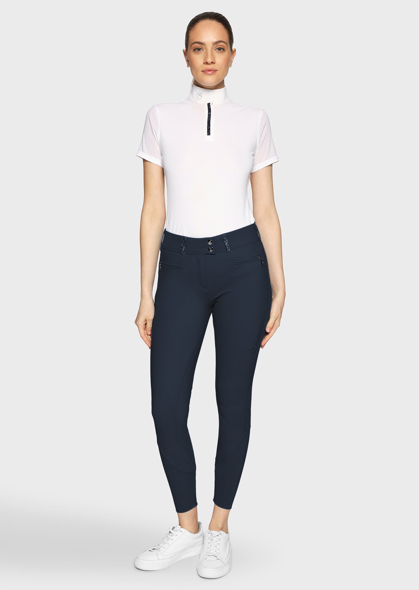 Woman wearing a white top and navy biker pants on a white background