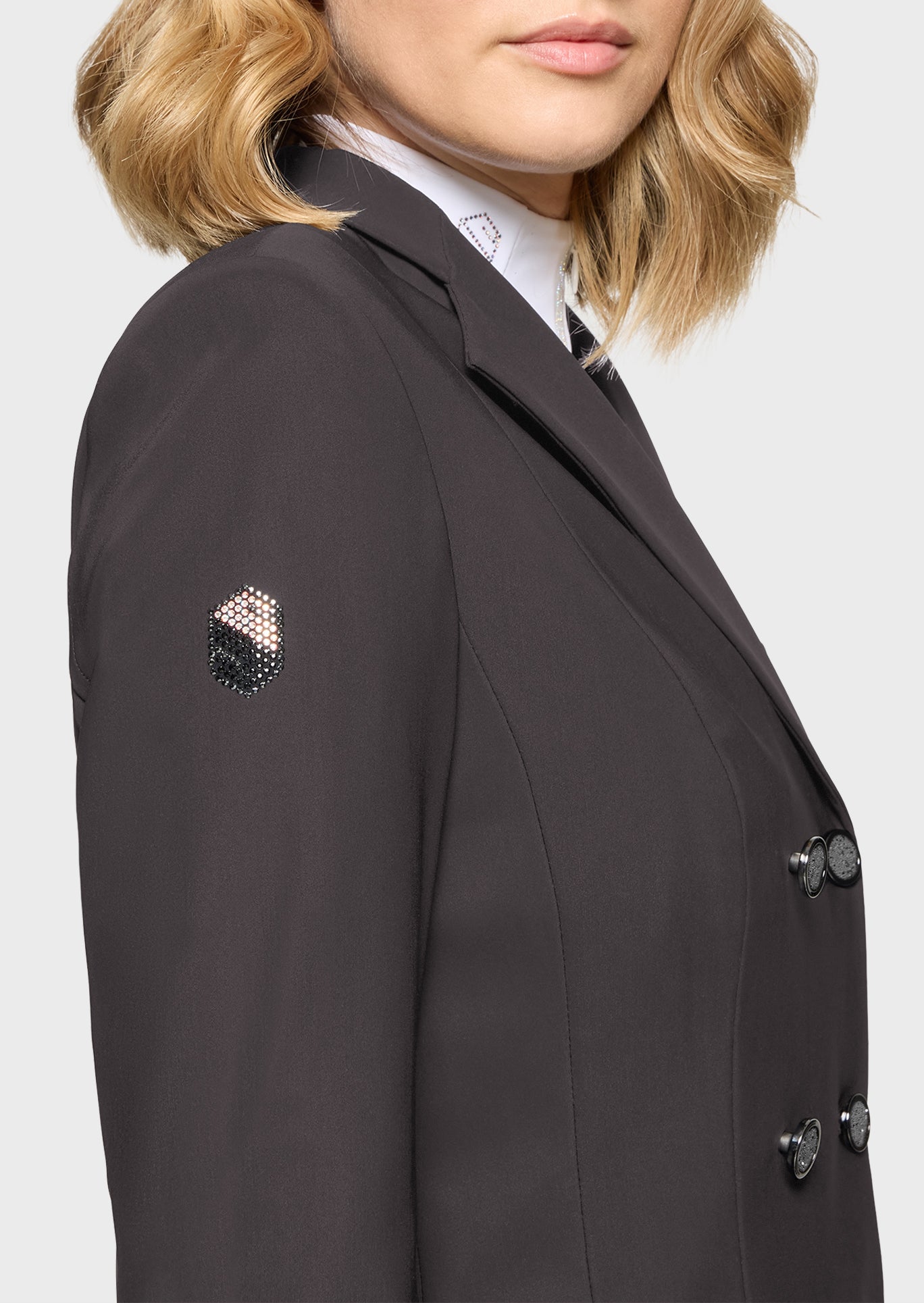 Black blazer with decorative buttons worn by a person on a light gray background
