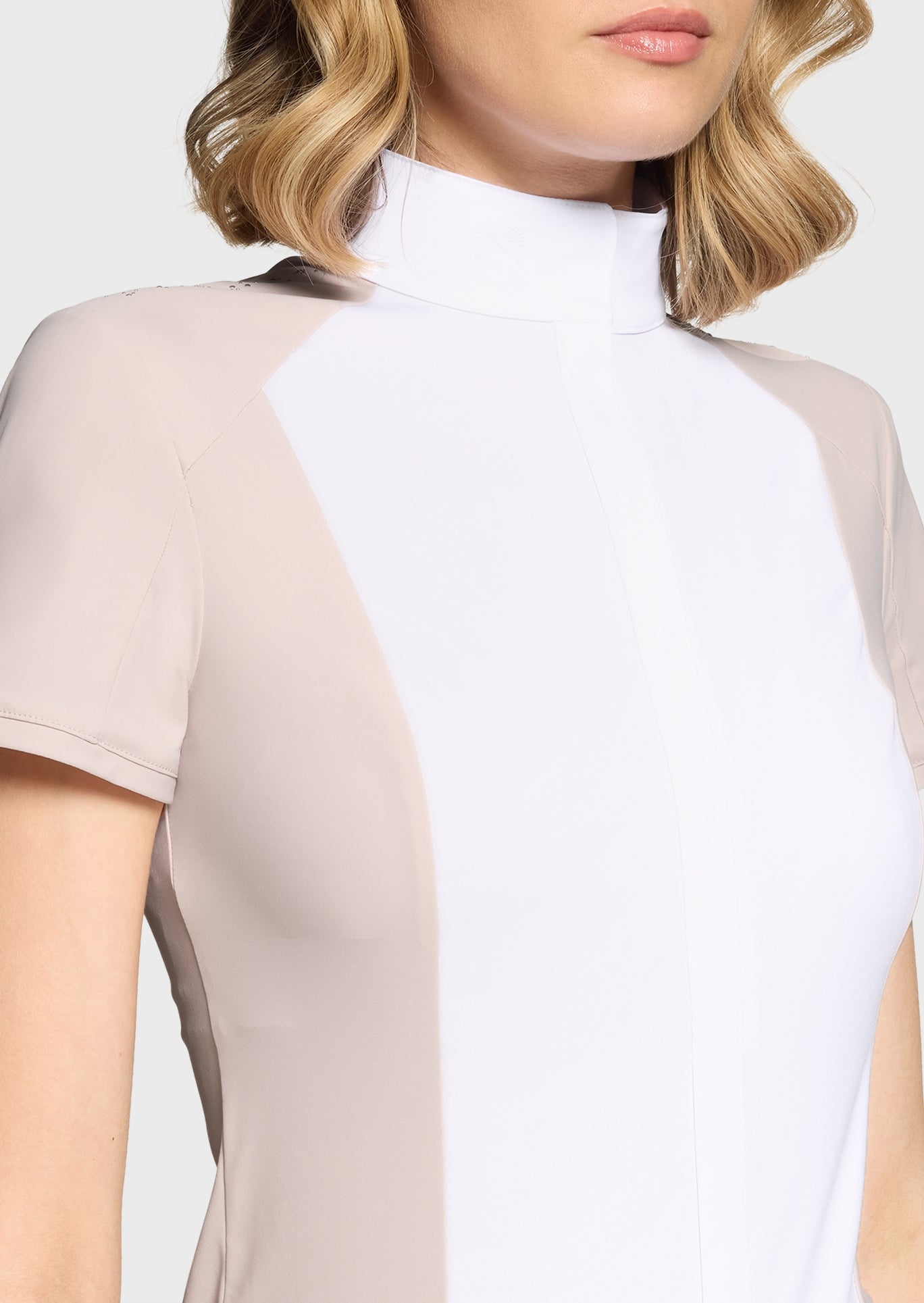 Close-up of a woman wearing a beige and white dress with sheer sleeves.