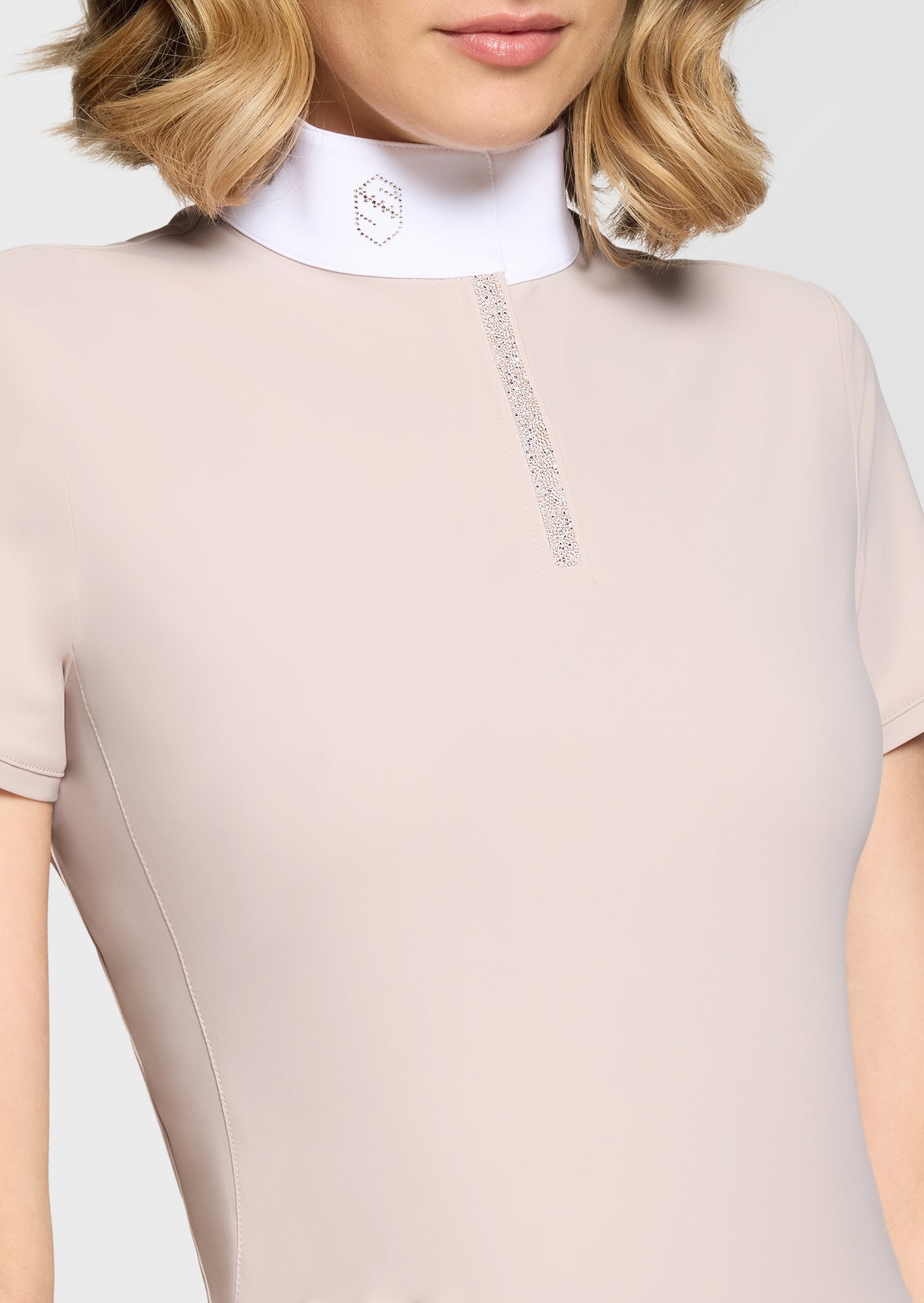 Beige equestrian jumpsuit with a white collar and brand logo on a plain background