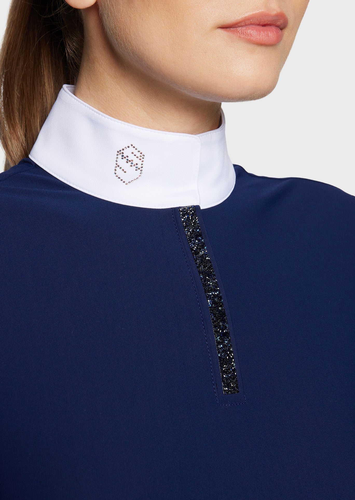 Close-up of a navy blue garment with a white collar and black embellishments on a light gray background