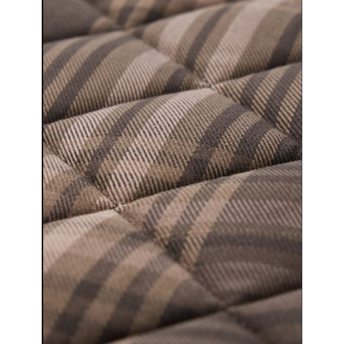 Close-up of a quilted fabric surface with a plaid pattern in beige, taupe, and dark brown.