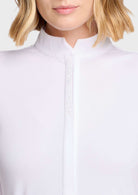 Close-up of a model wearing a white mock neck top with a decorative vertical line of small rhinestones down the center front.