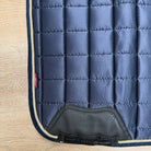 A close-up of a quilted navy blue horse saddle pad 