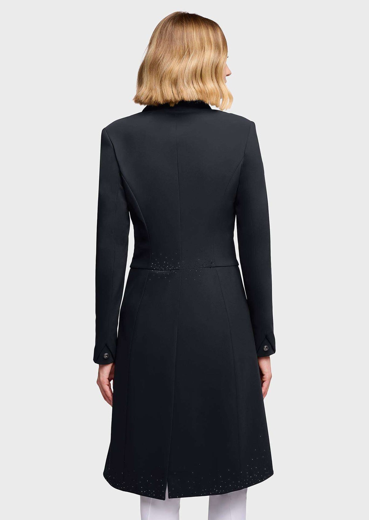 A woman shown from the back wearing a black longline coat with structured shoulders, long sleeves, and subtle embroidered detailing near the waist and hem, against a light gray studio background.