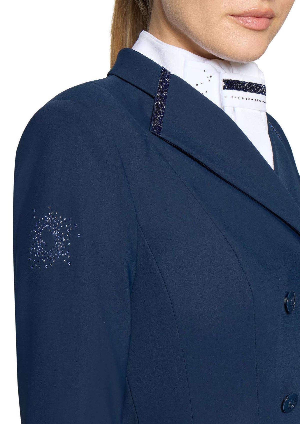 Close-up of a navy blue equestrian jacket with decorative silver rhinestone embroidery on the sleeve and lapel, worn by a model over a white high-collar shirt.