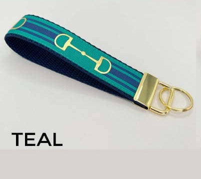 Teal key fob with gold horse bit design on a white background