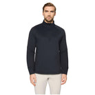 A man wearing a dark navy long-sleeve quarter-zip pullover with a small embroidered logo on the left chest, paired with light beige pants, against a solid light gray background.
