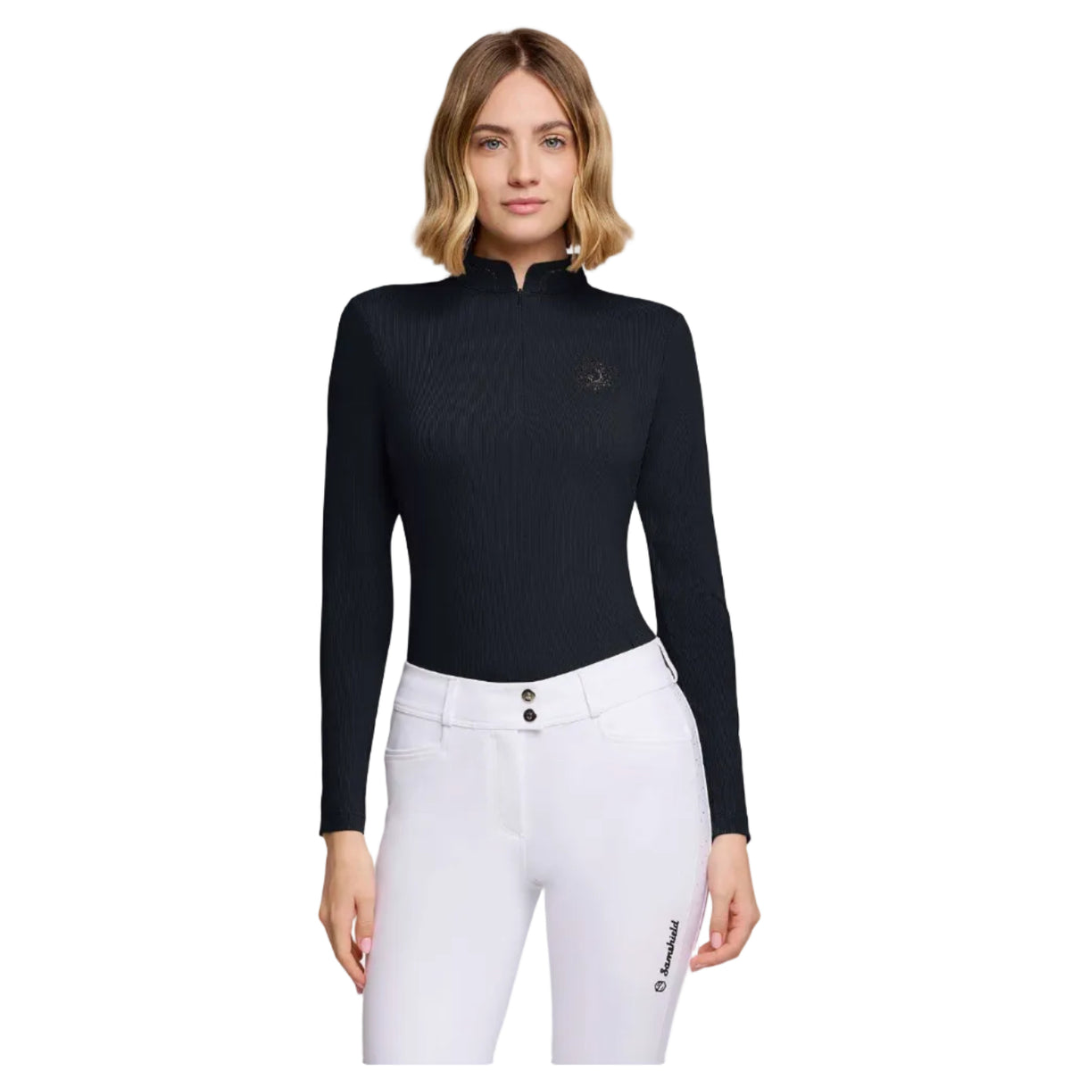 A woman modeling a black long-sleeve quarter-zip equestrian shirt with a small embroidered logo on the left chest, paired with white riding pants, against a plain white background.