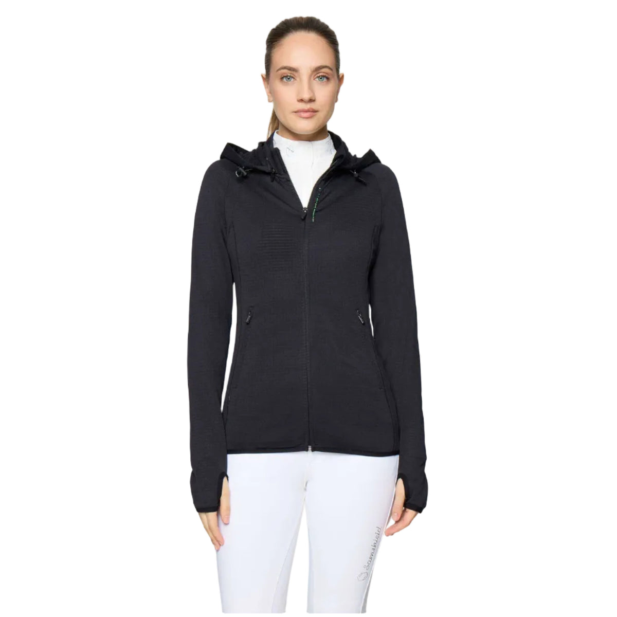 A woman modeling a black hooded zip-up athletic jacket over a white top and white pants, photographed against a light gray studio background.