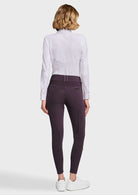 A woman shown from the back wearing a white long-sleeve button-up shirt, black skinny jeans, and white sneakers against a light gray studio background.