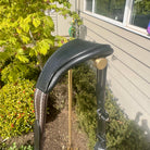 Black leather archery bow grip with gold accent on a stand outdoors.