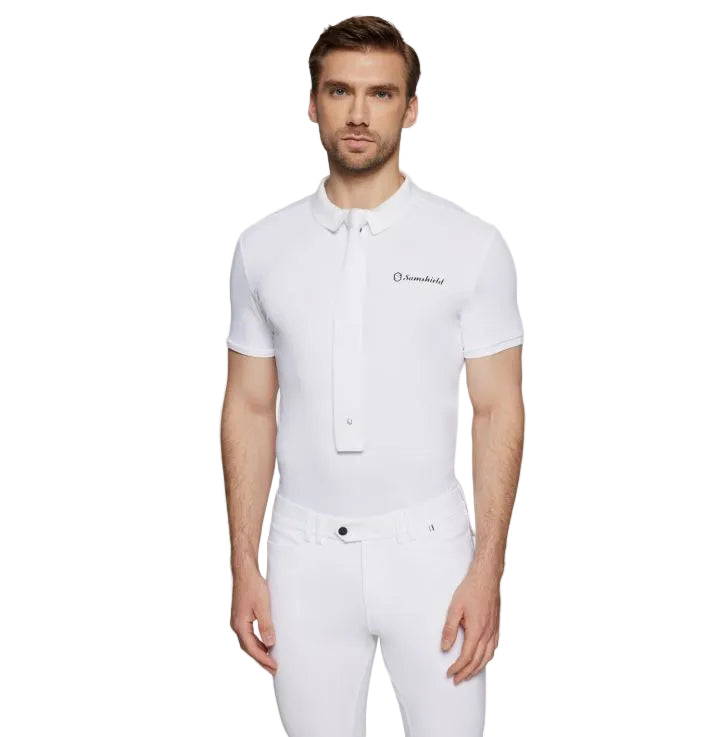A man modeling a white short-sleeve polo shirt with a white button-down collar and a small black embroidered logo on the left chest, paired with white trousers, against a light gray studio background.
