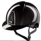 A glossy black equestrian riding helmet with a chin strap, featuring a silver-trimmed vented side panel with a visible KEP logo