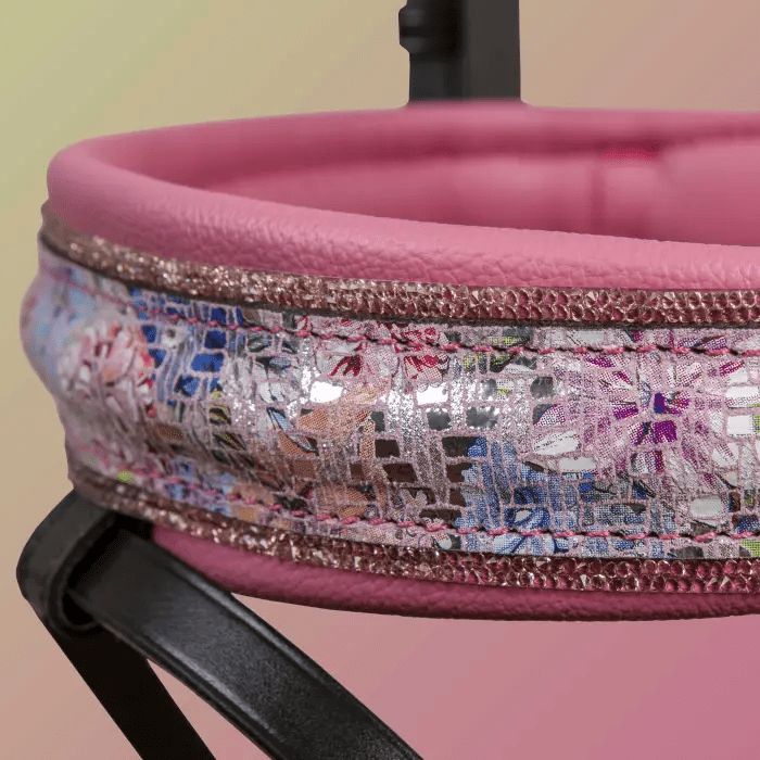 Close-up of a decorative pink and floral leather detail on a horse bridle.