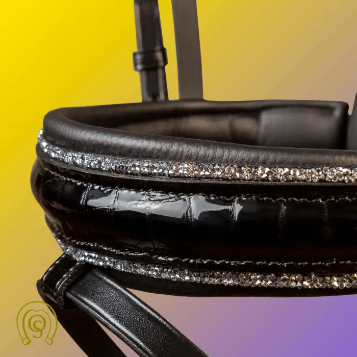 Close-up of a black horse bridle with sparkling embellishments on a gradient background.