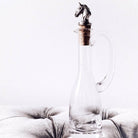 Glass decanter with horse head stopper on a light gray cushion