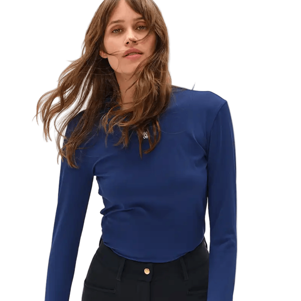 A woman wearing a fitted royal blue long-sleeve top with a small silver chest emblem, paired with black pants, against a plain white background.