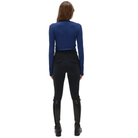 A woman viewed from the back wearing a royal blue long-sleeve top, black riding breeches, and tall black riding boots against a plain white background.