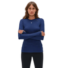 A woman modeling a royal blue long-sleeve athletic top with a small white logo on the chest, paired with black leggings, against a plain white background.