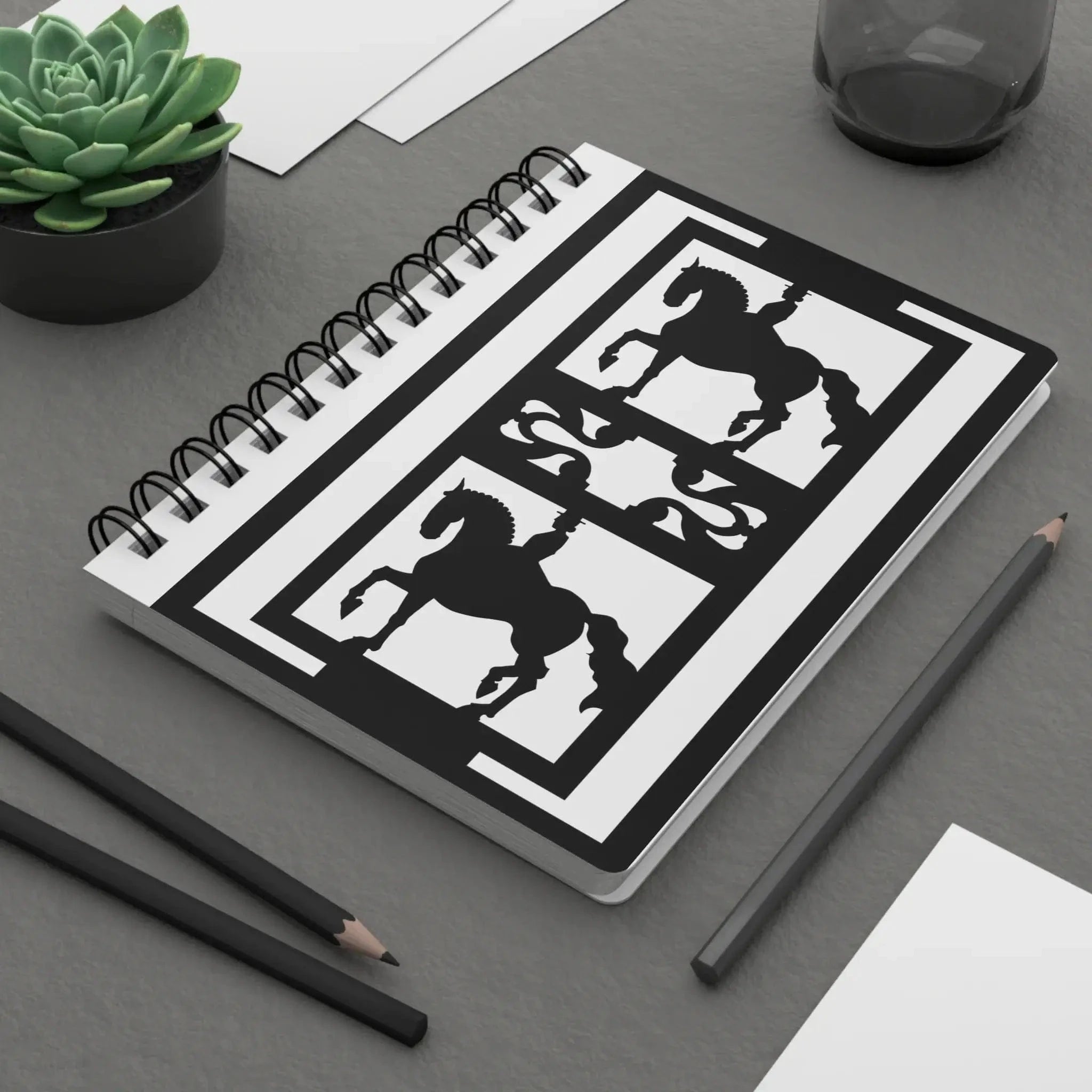 Notebook with horse illustrations on a desk with pencils and a plant
