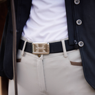 Person wearing a black belt with a gold buckle, white shirt, and beige pants.