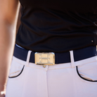 Navy belt with a gold buckle worn by a person, with a focus on the belt and part of the shirt.