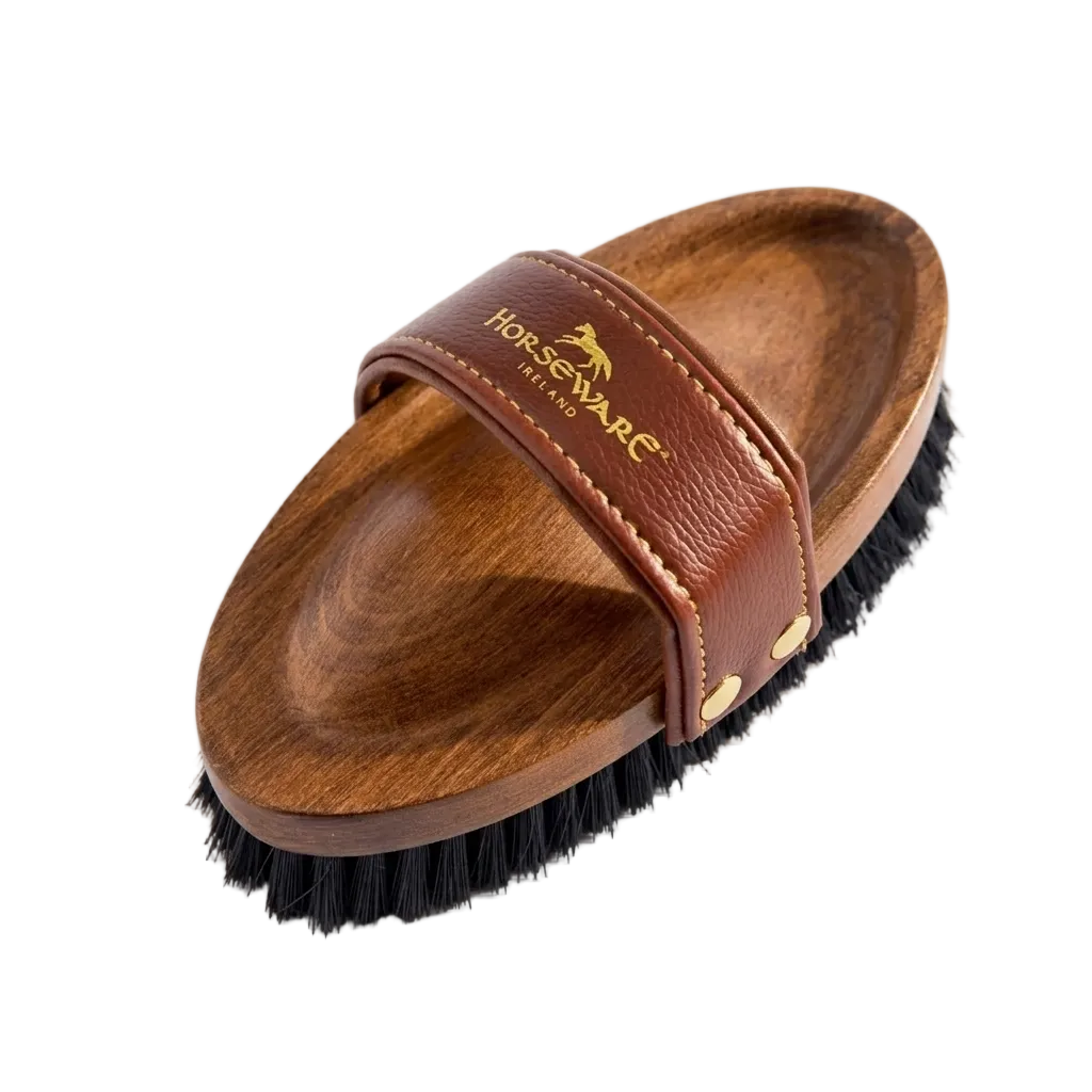 Wooden horse brush with brown leather strap on a white background