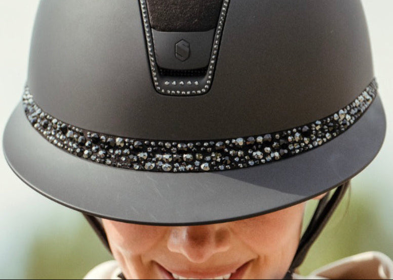 Gray riding helmet with decorative band on a blurred background