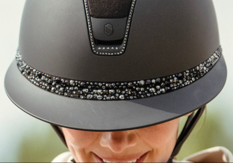 Gray riding helmet with decorative band on a blurred background