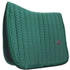 A dark teal green quilted equestrian saddle pad with a chevron pattern and a small diamond-shaped logo patch on the right side, set against a plain off-white background.