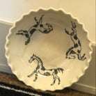 White ceramic dish with black horse illustrations on a textured surface