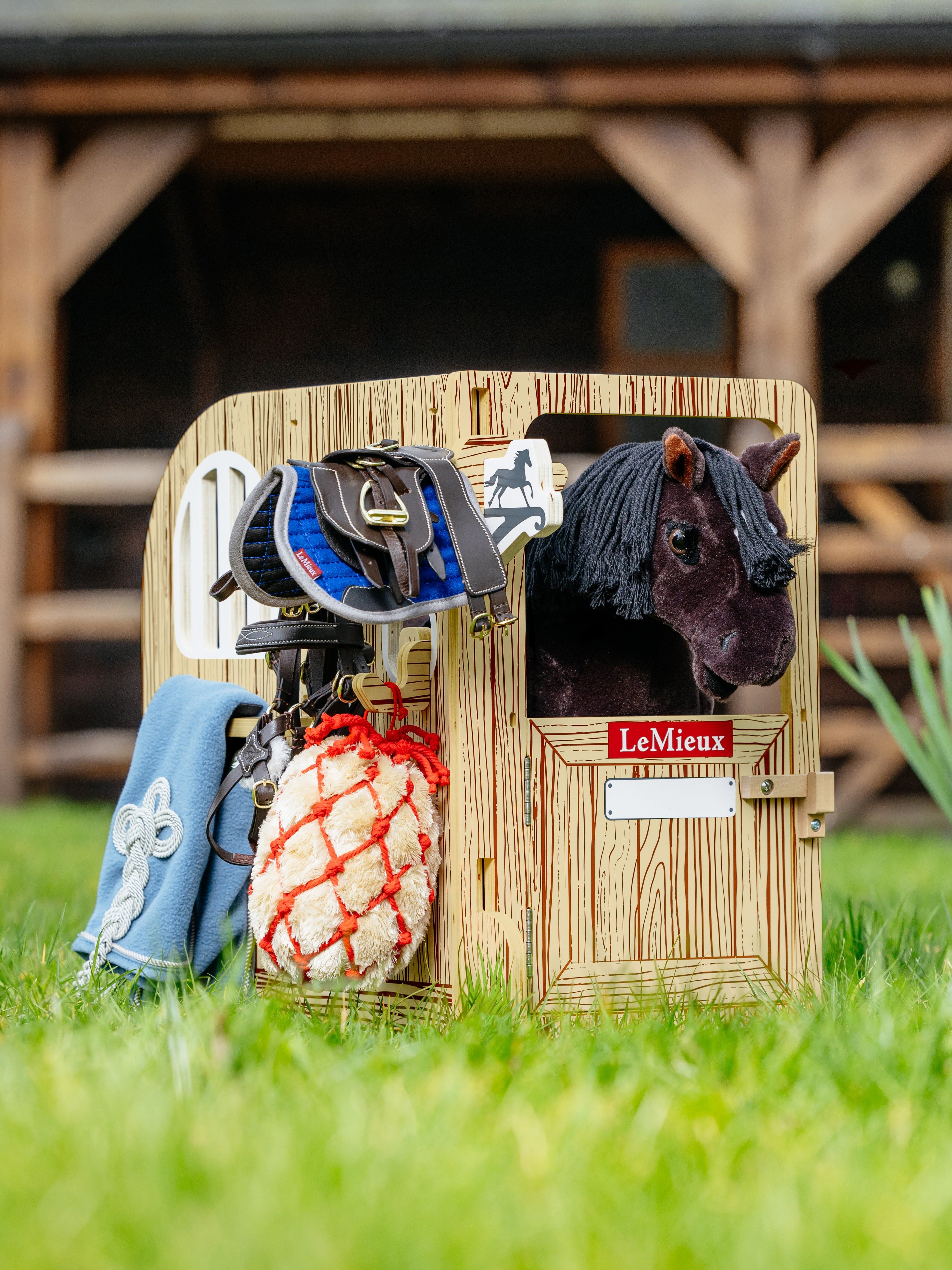 Horse stable with horse accessories on a grassy field