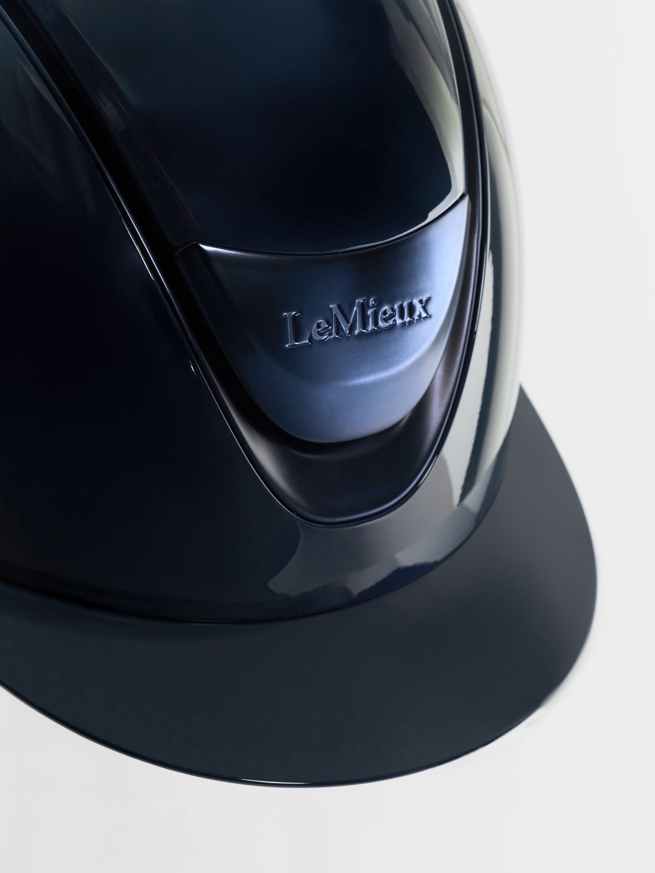 Close-up of a glossy black LeMieux riding helmet showing the front visor and embossed brand logo on a light gray background.