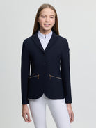 Person wearing a navy equestrian jacket on a light gray background