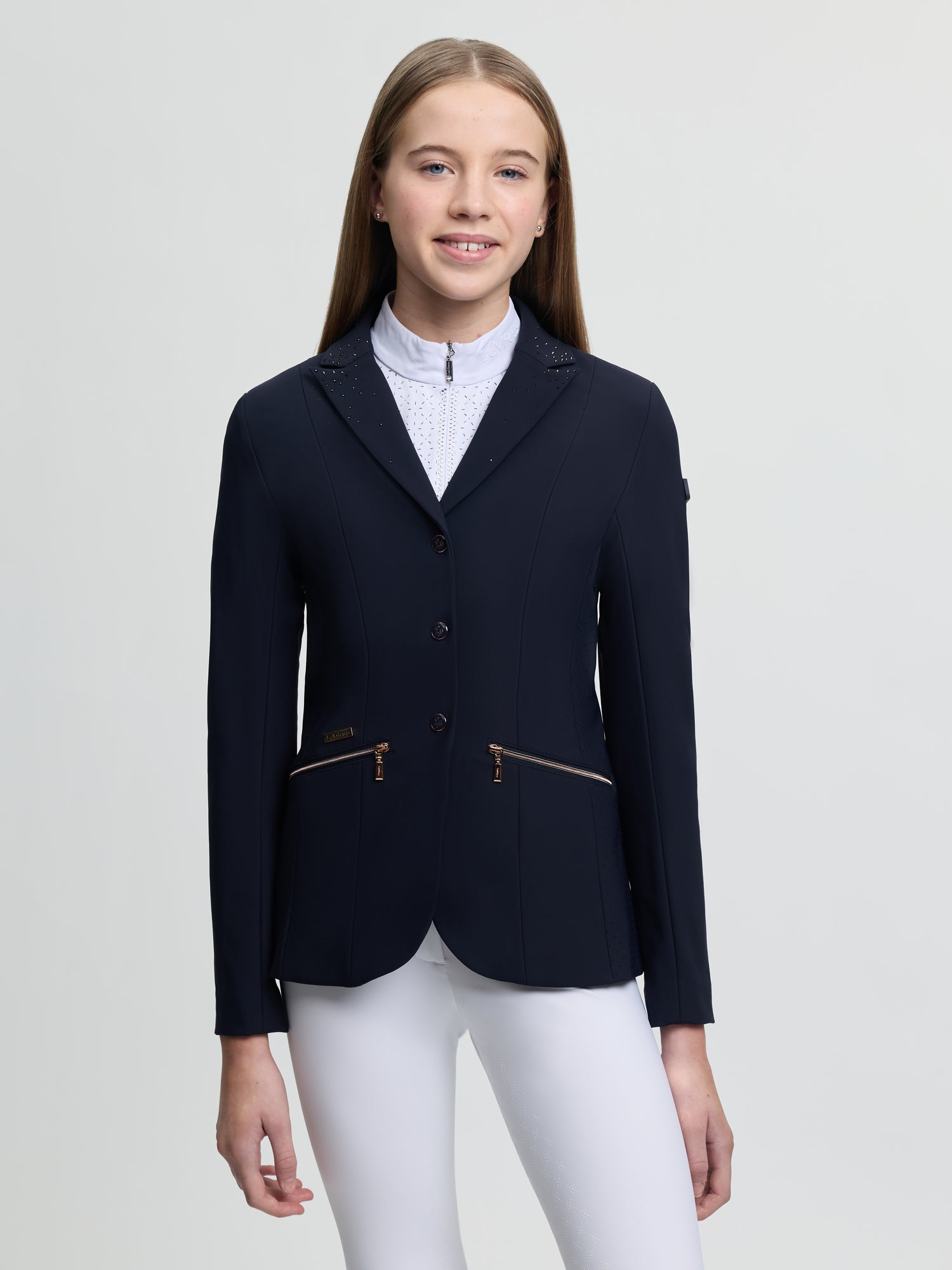 Person wearing a navy equestrian jacket on a light gray background