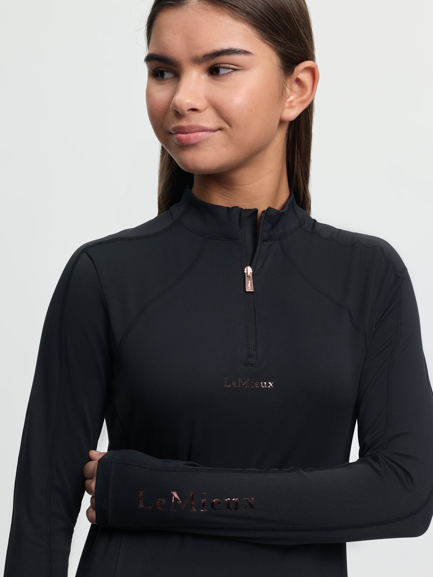 Woman wearing a black long-sleeve top with 'LeMieux' branding on a light gray background