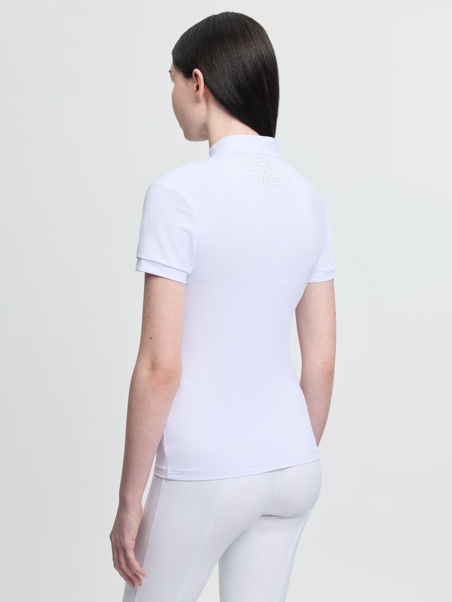 Person wearing a white polo shirt and pants on a light gray background