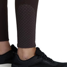 Black LeMieux athletic sneakers with a thick white sole, shown on a model wearing dark brown textured leggings against a light gray studio background.